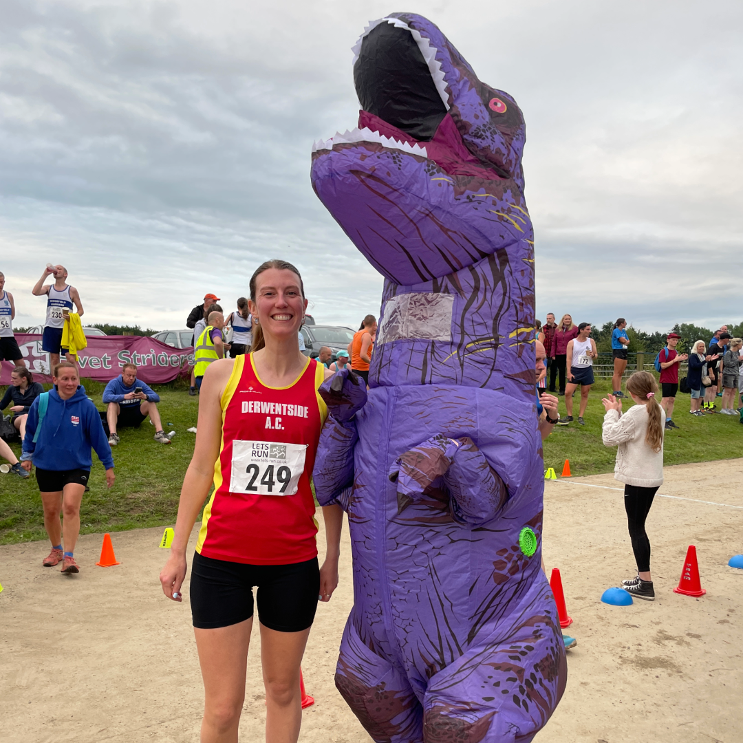 A picture of Rosie after a race standing next to someone dressed as a purple dinosaur